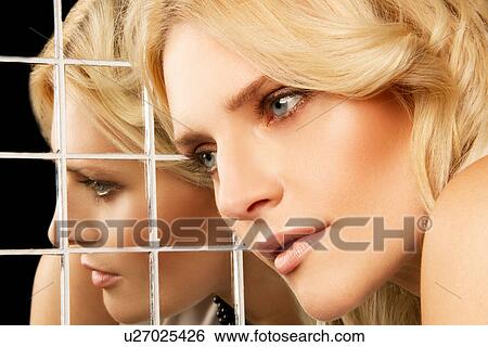 Stock Photograph - Portrait of woman posing against mirror. Fotosearch