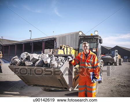 Stock Photo - Portrait of worker in reflective workwear with dumper of crushed titanium. Fotosearch