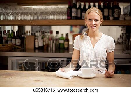 Stock Photography - Portrait of young waitress behind coffee bar counter. Fotosearch