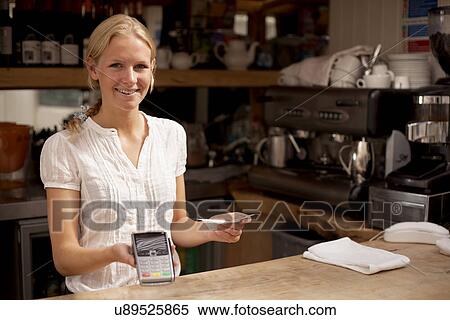Portrait of young waitress holding credit card reader at kitchen counter View Large Photo Image Stock Photography - Portrait of young waitress holding credit card reader at kitchen counter. Fotosearch