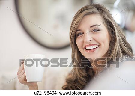 Portrait of young woman holding coffee mug View Large Photo Image Picture - Portrait of young woman holding coffee mug. Fotosearch