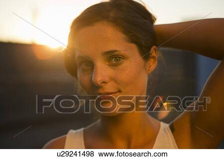 Stock Photo - Portrait of young woman holding her hair back. Fotosearch