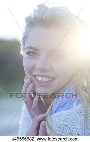 Stock Image - Portrait of young woman huddled up in blanket. Fotosearch