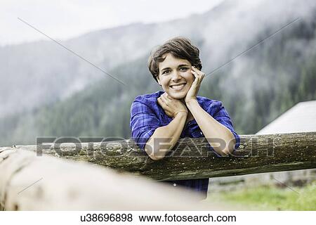 Portrait of young woman leaning against fence, Tyrol Austria View Large Photo Image Stock Photo - Portrait of young woman leaning against fence, Tyrol Austria. Fotosearch