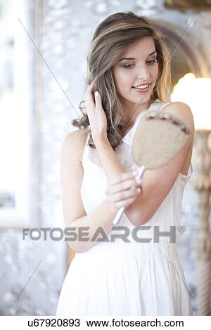 Portrait of young woman looking in hand mirror View Large Photo Image Stock Image - Portrait of young woman looking in hand mirror. Fotosearch