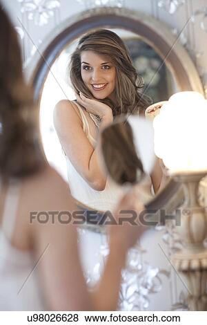 Portrait of young woman looking in wall mirror View Large Photo Image Stock Photo - Portrait of young woman looking in wall mirror. Fotosearch
