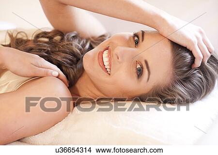 Picture - Portrait of young woman lying on bed. Fotosearch