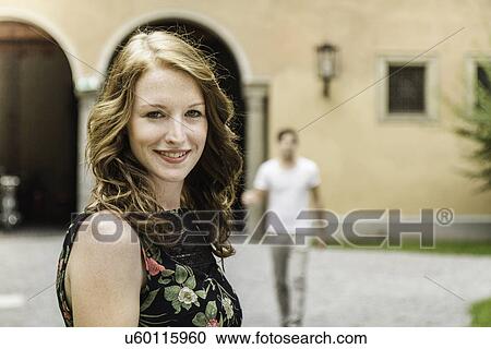 Portrait of young woman, man in background View Large Photo Image Stock Image - Portrait of young woman, man in background. Fotosearch