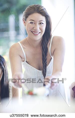 Portrait of young woman serving meal to friends View Large Photo Image Stock Photo - Portrait of young woman serving meal to friends. Fotosearch