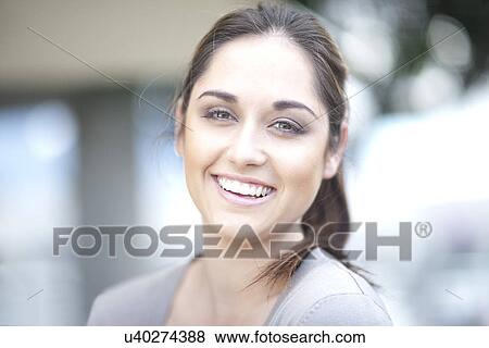 Stock Photo - Portrait of young woman, smiling, hair up. Fotosearch