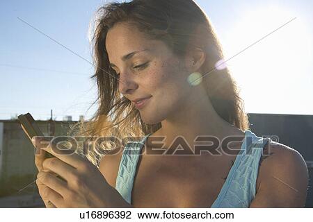 Stock Image - Portrait of young woman using mobile phone. Fotosearch