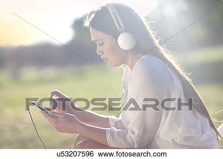 Stock Photograph - Portrait of young woman with digital tablet and earphones. Fotosearch