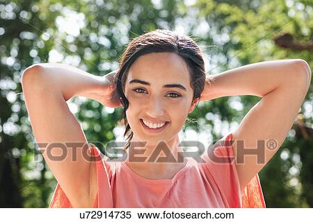 Portrait of young woman with hands behind head View Large Photo Image Stock Photography - Portrait of young woman with hands behind head. Fotosearch