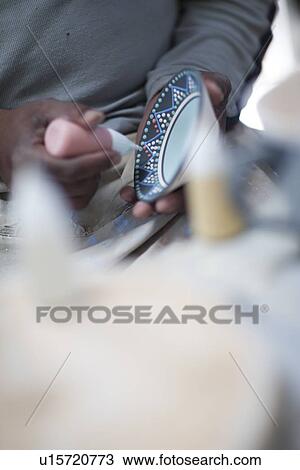 Stock Image - Potter finishing design on plate. Fotosearch