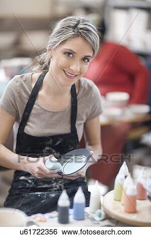 Stock Photograph - Potter painting plate at crockery factory. Fotosearch
