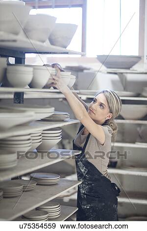 Potter stacking bowls onto shelf at crockery factory View Large Photo Image Stock Photo - Potter stacking bowls onto shelf at crockery factory. Fotosearch