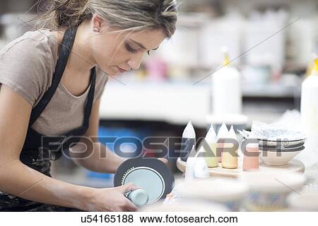 Stock Photo - Potter starting design on plate at crockery factory. Fotosearch