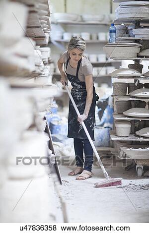 Stock Photo - Potter sweeping floor at crockery factory. Fotosearch