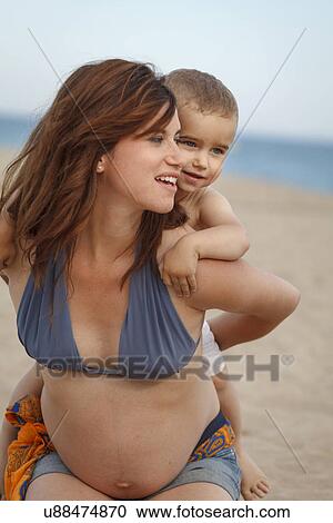 Stock Image - Pregnant mother giving toddler piggy back. Fotosearch