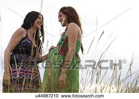 Pregnant woman and friend, standing in long grass View Large Photo Image Stock Image - Pregnant woman and friend, standing in long grass. Fotosearch