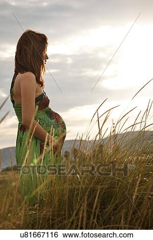 Pregnant woman standing in field View Large Photo Image Stock Photograph - Pregnant woman standing in field. Fotosearch