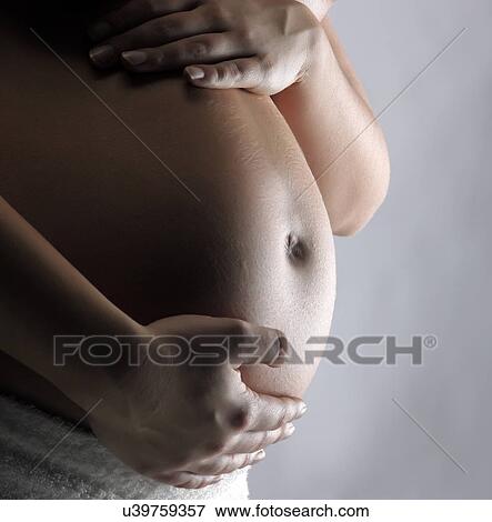 Pregnant woman supporting tummy View Large Photo Image Stock Photo - Pregnant woman supporting tummy. Fotosearch