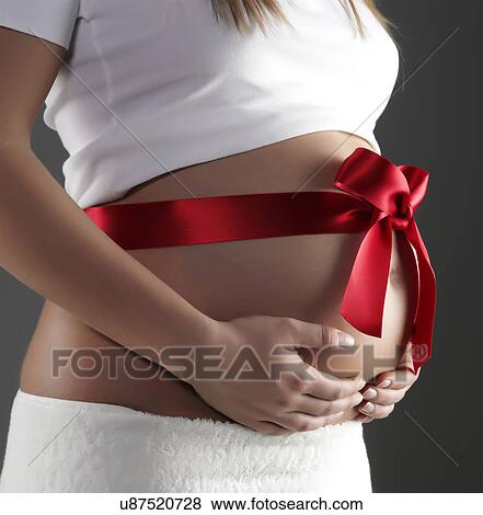 Pregnant woman's belly with red gift bow View Large Photo Image Stock Photo - Pregnant woman's belly with red gift bow. Fotosearch