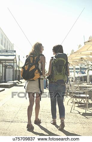 Rear view of woman walking along street carrying backpacks View Large Photo Image Stock Photo - Rear view of woman walking along street carrying backpacks. Fotosearch