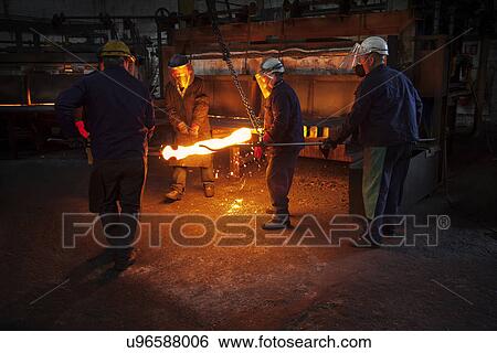 Stock Photograph - Red hot steel billet which has already been partially pre formed is moved back in to the furnace. Fotosearch
