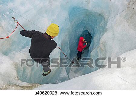 Stock Photo - Rock climbers moving down ice cave Fox Glacier, South Island, New Zealand. Fotosearch