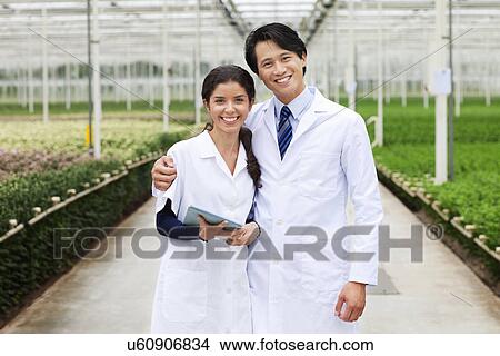 Scientists in greenhouse, arm around View Large Photo Image Picture - Scientists in greenhouse, arm around. Fotosearch