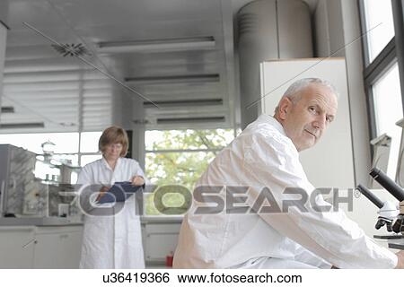 Scientists working in laboratory, man with microscope and woman taking notes View Large Photo Image Stock Photograph - Scientists working in laboratory, man with microscope and woman taking notes. Fotosearch