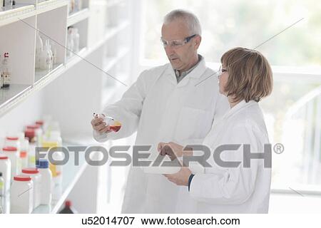 Stock Photo - Scientists working in laboratory, sample in glass bottle. Fotosearch