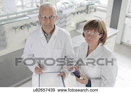 Scientists working in laboratory, holding blue liquid in vial View Large Photo Image Stock Photo - Scientists working in laboratory, holding blue liquid in vial. Fotosearch