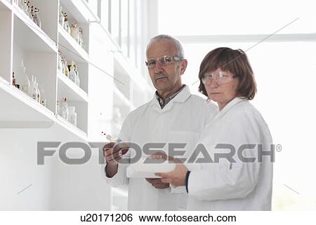 Scientists working in laboratory, sample in glass bottle View Large Photo Image Stock Photograph - Scientists working in laboratory, sample in glass bottle. Fotosearch