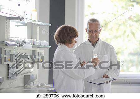 Scientists working in laboratory, holding vial View Large Photo Image Stock Photograph - Scientists working in laboratory, holding vial. Fotosearch