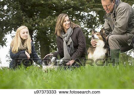Stock Image - Senior couple and granddaughter out with dogs. Fotosearch