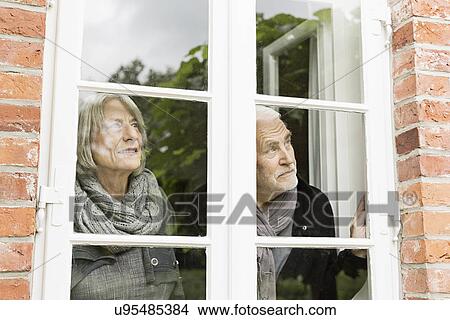 Picture - Senior couple looking through window. Fotosearch