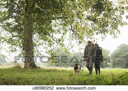 Senior couple walking dog, Norfolk, UK View Large Photo Image Stock Image - Senior couple walking dog, Norfolk, UK. Fotosearch