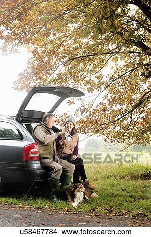 Senior couple with dogs sharing coffee from car boot, Norfolk, UK View Large Photo Image Picture - Senior couple with dogs sharing coffee from car boot, Norfolk, UK. Fotosearch