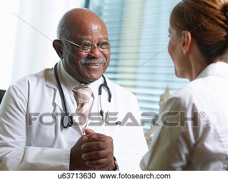 Stock Image - Senior doctor with female patient. Fotosearch