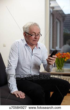 Senior man at home texting on mobile phone View Large Photo Image Stock Photo - Senior man at home texting on mobile phone. Fotosearch