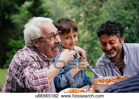 Senior man enjoying food with grandson and son View Large Photo Image Stock Image - Senior man enjoying food with grandson and son. Fotosearch