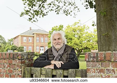 Picture - Senior man leaning on wooden gate. Fotosearch