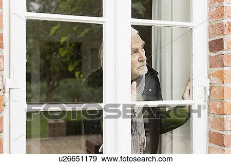 Senior man looking through window View Large Photo Image Stock Photo - Senior man looking through window. Fotosearch