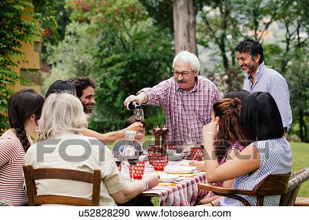 Senior man pouring wine at family meal View Large Photo Image Stock Image - Senior man pouring wine at family meal. Fotosearch
