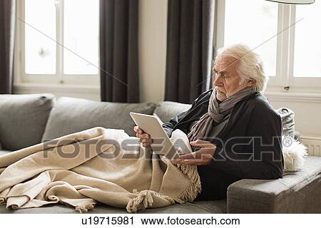 Senior man using digital tablet with blanket View Large Photo Image Stock Image - Senior man using digital tablet with blanket. Fotosearch