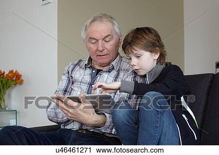 Senior man with grandson at home using digital tablet View Large Photo Image Stock Image - Senior man with grandson at home using digital tablet. Fotosearch