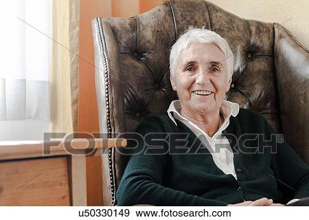 Senior woman sitting on armchair View Large Photo Image Stock Photo - Senior woman sitting on armchair. Fotosearch