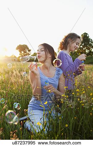 Sisters blowing bubbles in field View Large Photo Image Stock Photography - Sisters blowing bubbles in field. Fotosearch